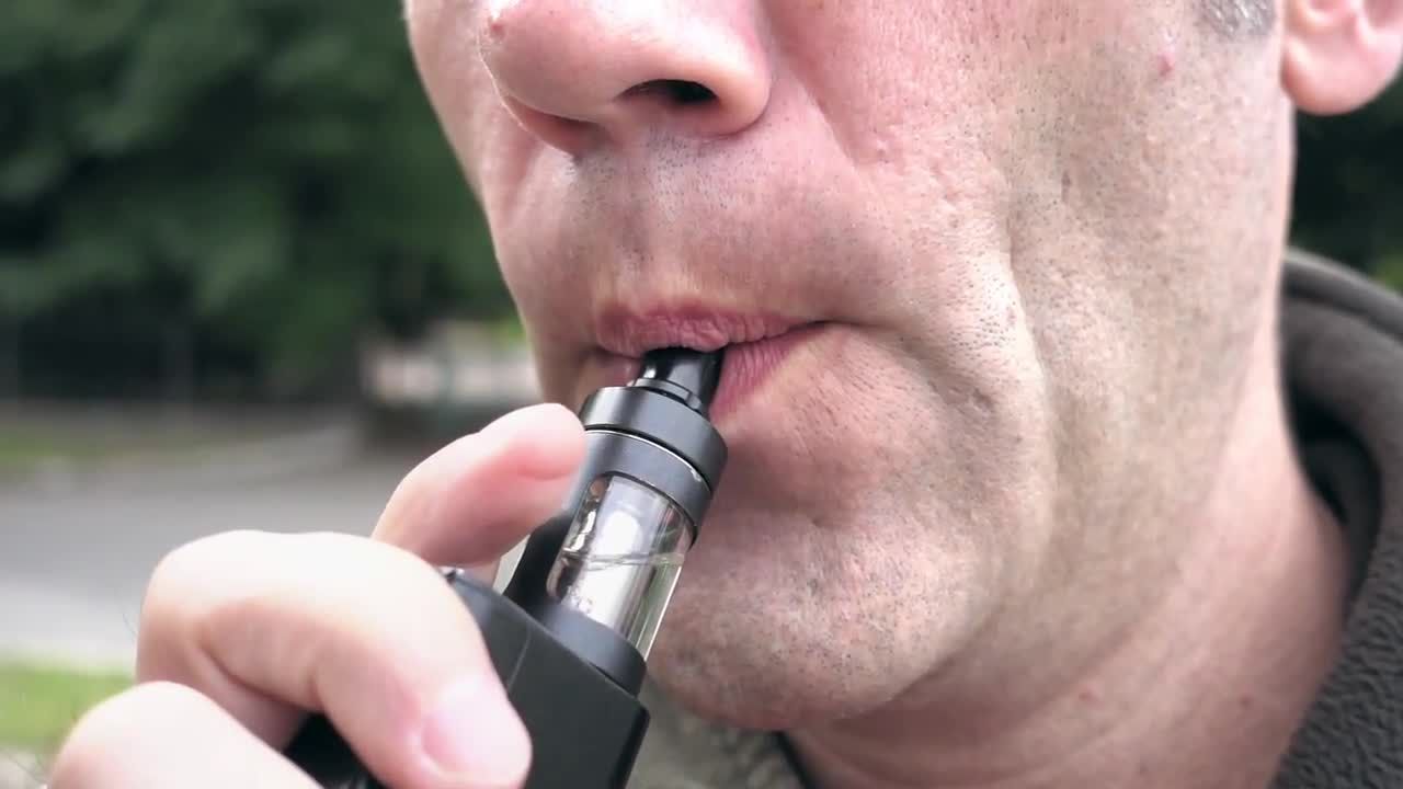 户外吸电子烟突出浓烟的男人实拍视频素材
