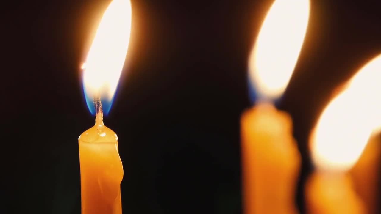 黑色背景前的三个黄色蜡烛燃烧视频