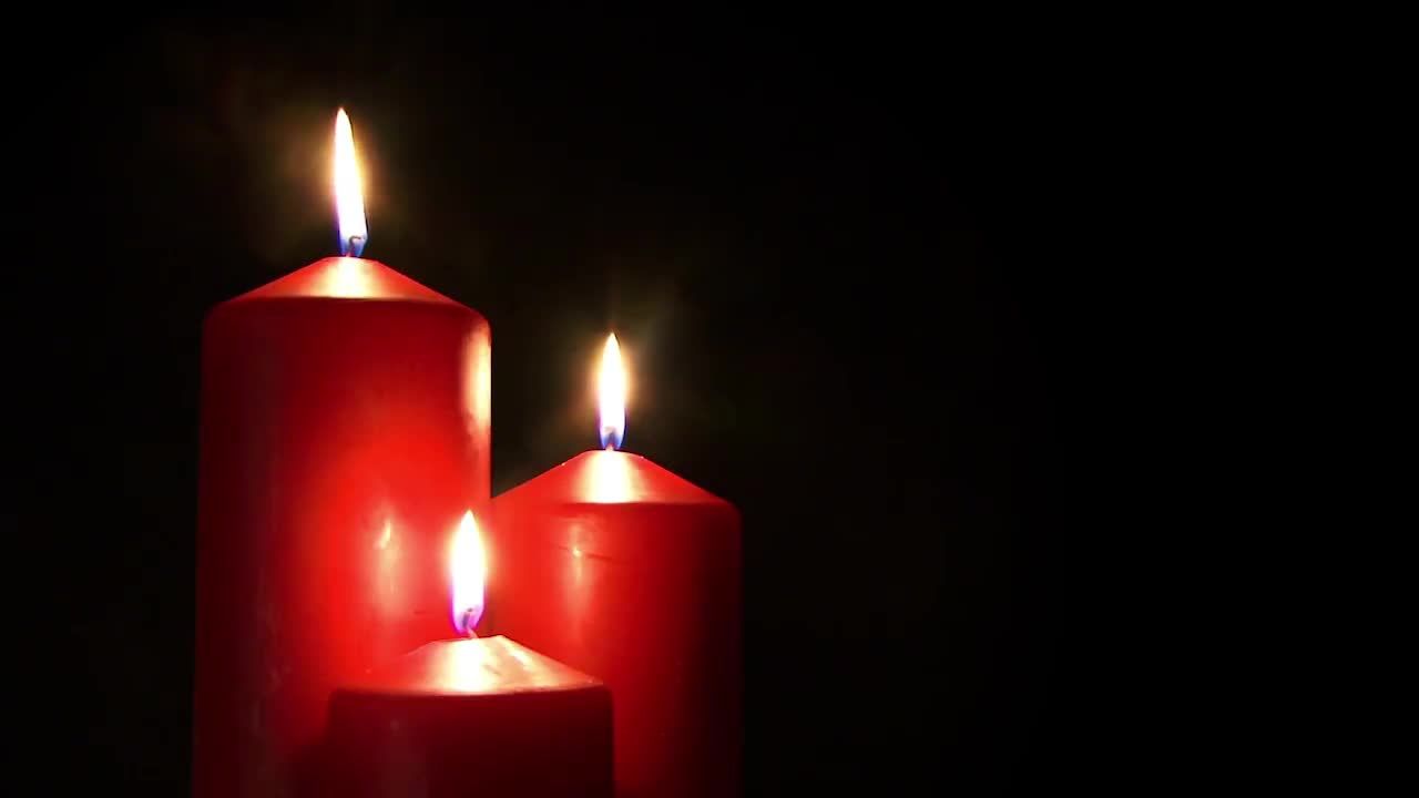 黑色背景下燃烧的三个红色蜡烛视频素材