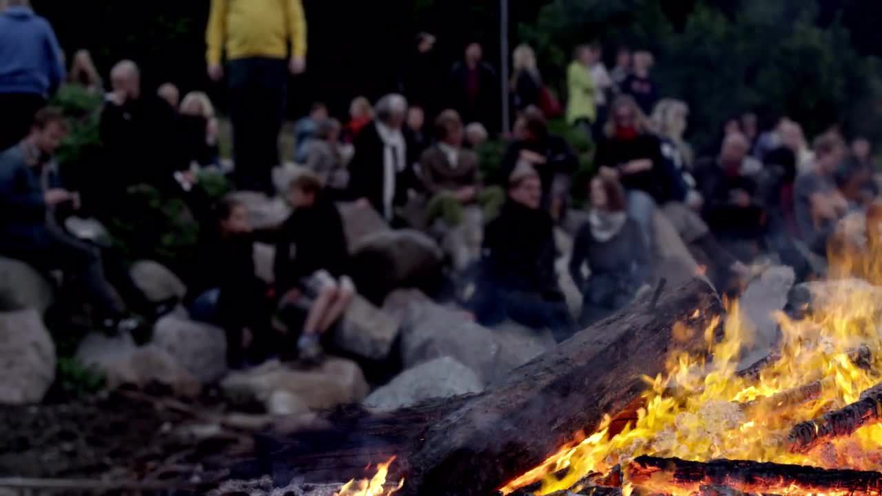 一群人坐在岸上观看燃烧的篝火视频素材