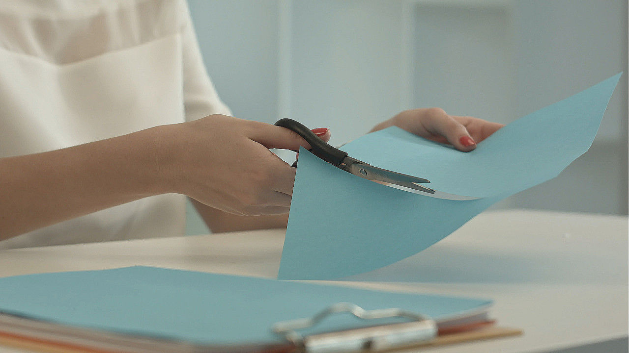 一个女人用剪刀剪蓝纸视频素材