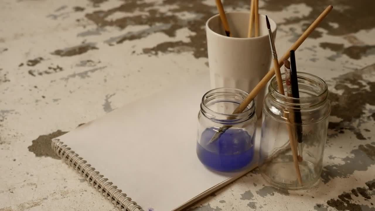 桌子上面的一张纸和玻璃罐中的画笔视频素材