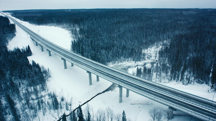森林上空拍摄的充满积雪的森林里长长的高速公路