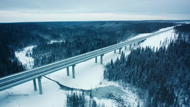 汽车沿着森林空中在漫长的白雪皑皑的高速公路上行驶