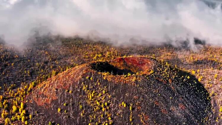 云和雾在火山与烧毁的树木空中实拍视频